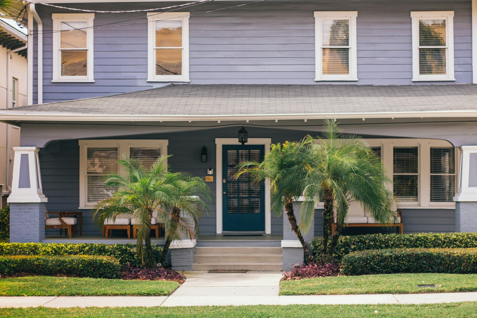 A blue Florida home with a welcoming front porch and palms